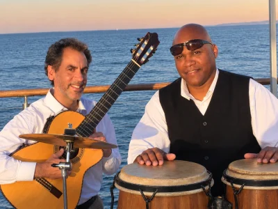 Tomas Rodriguez performing as a duo with a percussionist at a waterfront event.